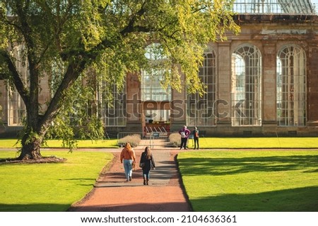 People walking at Edinburgh greenhouse Palm Houses are dramatic landmarks in Royal Botanic Garden Edinburgh history of caring for tender plants under glass  with a roof of curvilinear iron rafter Royalty-Free Stock Photo #2104636361
