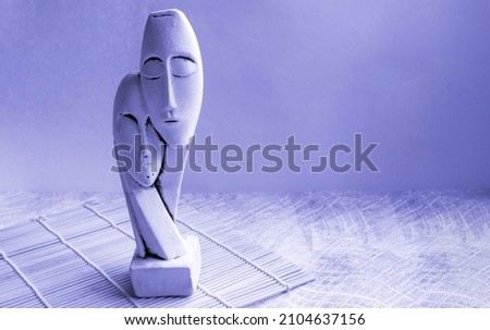 A statuette of a couple isolated on a lilac background very peri. The face of a man and a woman. place for your text.