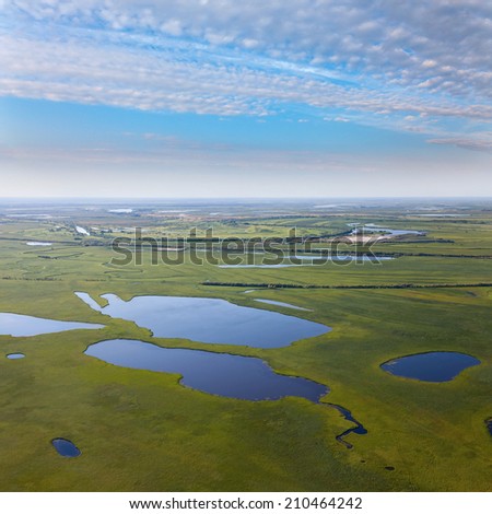 Aerial view the lakes which are located in area of green meadows of the flood-land of the river.