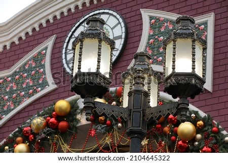 Lantern on background of building decorated for Christmas red and gold balls garland and fir branch in festive new year street design in europe close up view