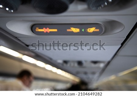 prohibition signs in airplane light up on control panel overhead with signal that shows crossed cigarette and recommendation to buckle up