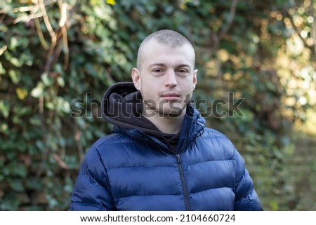 Stock photo of a portrait of a young man posing in nature one cold sunny day.