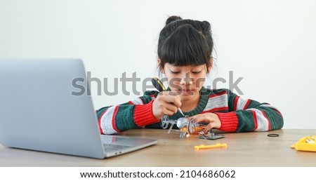 The little girl asian building robotic car in science lesson in the house . Which increases the development and enhances learning skills gifted brilliant children working with technology. Royalty-Free Stock Photo #2104686062
