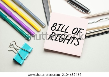 Reports and color charts are on the table. There are also red pens, pencil and paper in a black frame with the words BILL OF RIGHTS