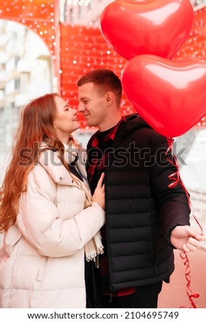 Young guy laughs and carries a beautiful girl on his back. Yellow bokeh in the background. Valentine's day concept, gifts, love, shopping