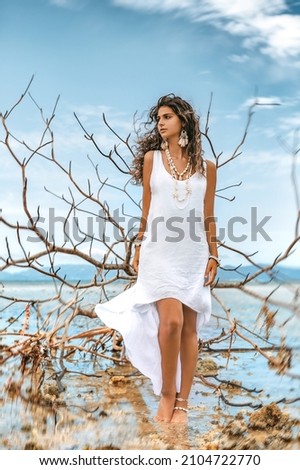 Beautiful young stylish woman in white dress on the beach
