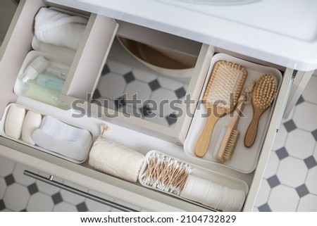 Marie Kondo's method organization of bathroom amenities in modern open shelf case. Toiletries in white stylish drawer or cupboard top view. Contemporary tidying up or storage household space Royalty-Free Stock Photo #2104732829