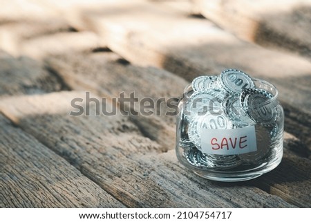 coins in a glass jar on wooden table. Saving money, money income, banking concept. Copy space for text.