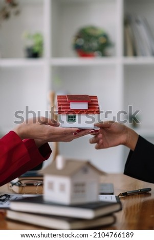 Real estate agent sales manager holding house model to customer after signing rental lease contract of sale purchase agreement, concerning mortgage loan offer for and house insurance