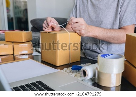 Young entrepreneur SME man receive order client and working with packaging sort box delivery online market on purchase order and preparing package product, Small business parcel for shipment. Royalty-Free Stock Photo #2104791275