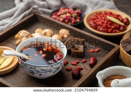 Brown sugar ginger jujube tea and Chinese classical medical books on the table