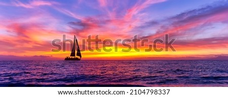 A Sailboat Is Sailing Along The Ocean Against A Colorful Sunset Sky Royalty-Free Stock Photo #2104798337
