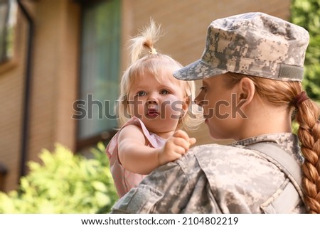 Sad baby girl with her military mother outdoors