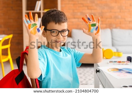 Little boy with hands in paint at home