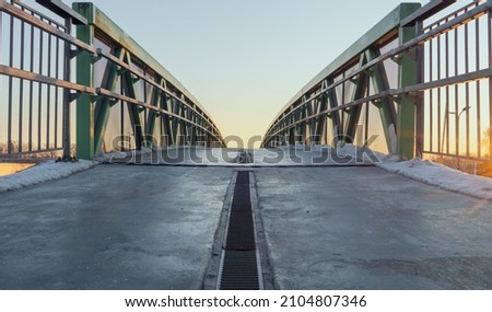 view on concrete pedestrian bridge with iron railings in sunset. winter