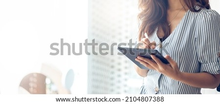 Focus on hand young asian businesswoman standing and using stylus pen writing on computer tablet to working or meeting online, panorama image