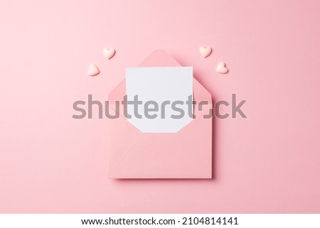 Top view photo of valentine's day decorations open pink envelope with paper sheet and pink hearts on isolated pastel pink background with empty space