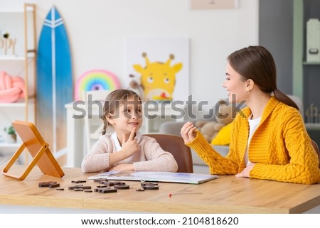 Speech therapist working with cute girl in clinic Royalty-Free Stock Photo #2104818620