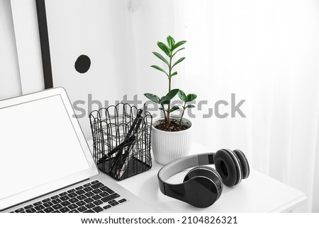 Black headphones with organizer and flowerpot on white table in room