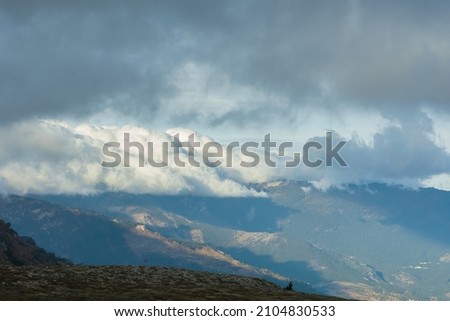 Low clouds of the mountain. Majestic huge clouds hung over the valley of the mountains. Atmospheric sunny landscape. The concept of travel, the beauty of nature, impressions. Landscape without people