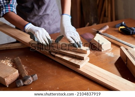 Woman work to making woodcraft furniture in wood workshop. Female carpenter working in carpentry shop with pencil drawing sign on plank. Girl professional high skill workman. 