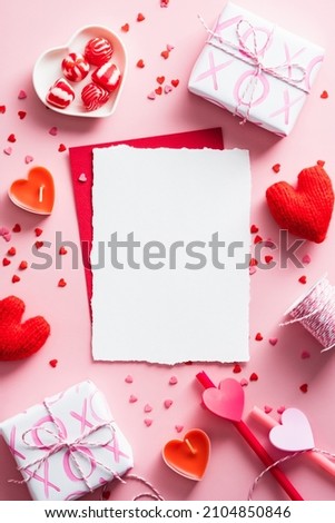 Vertical Valentines Day background with blank paper card mockup, gifts, red hearts, confetti on pink. Royalty-Free Stock Photo #2104850846