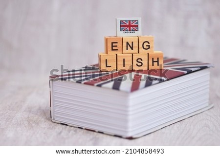 THe wooden cube "ENGLISH" alphabet with the union flag on  the english book. English is the language of science, aviation, computers, diplomacy, and tourism. It's an official language for many countr  Royalty-Free Stock Photo #2104858493