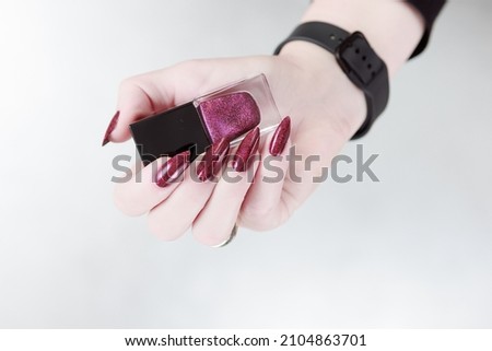 Female hands with long nails and dark red nail polish