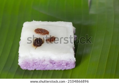 Thai sweet sticky rice cake with coconut milk and currant topping on banana leaf background.