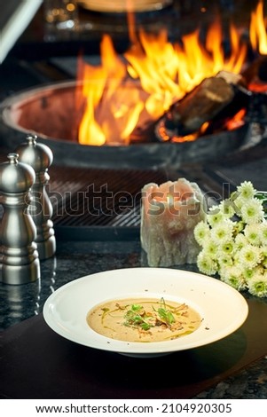 Cream of mushroom soup with truffle on the background of fire. Selective focus, close-up. Noise grain in post-production