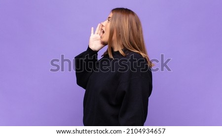 young blonde woman profile view, looking happy and excited, shouting and calling to copy space on the side