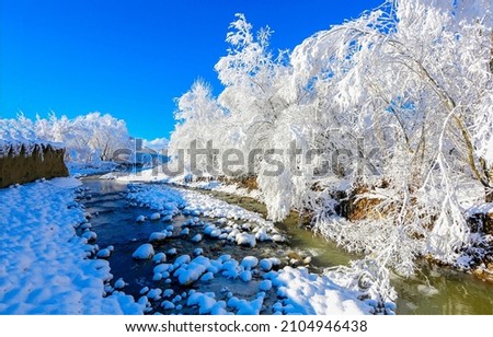 Snowy river in winter landscape. Forest river in winter snow scene. River in winter snow forest. Winter snow scene Royalty-Free Stock Photo #2104946438