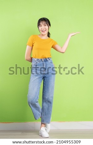 Young Asian woman posing on green background Royalty-Free Stock Photo #2104955309