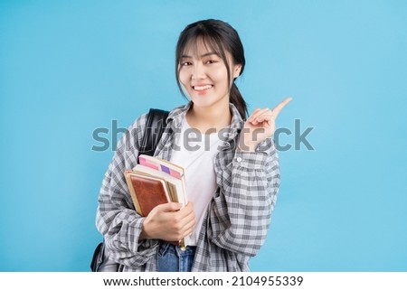 Young Asian student on blue background
