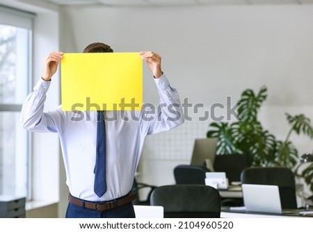 Young man with blank paper sheet in office