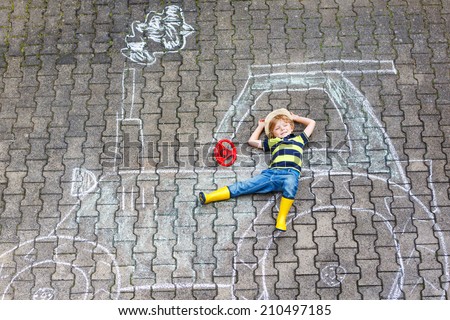 Funny little child having fun with tractor picture drawing with chalk.