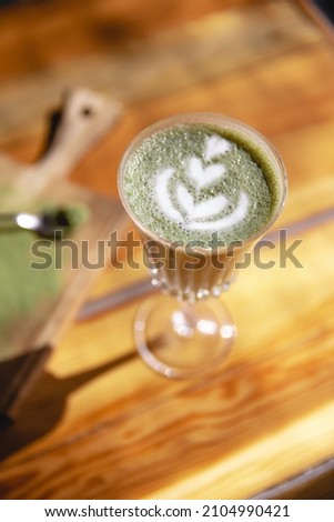Pistachio coffee in the glass with cream or milk, top view on beautiful wooden background. Great picture for baner or menu