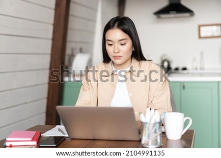 Young korean woman working on laptop from home. Girl writing on computer keyboard, studying online or doing homework, writes project on pc