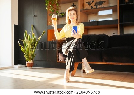 an adult woman takes a selfie at home with a glass of wine
