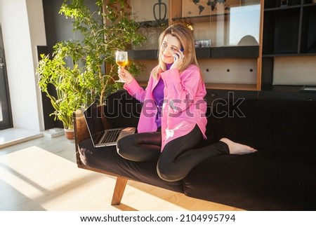 an adult woman on the couch with a laptop and a glass of wine