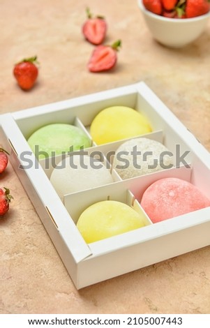 Box with tasty Japanese mochi and strawberry on color background, closeup