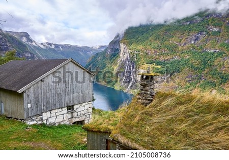 view of a typical norwagian house in geirangerfjord in norway. in the center of the picture there is the seven  sisters waterfall. 