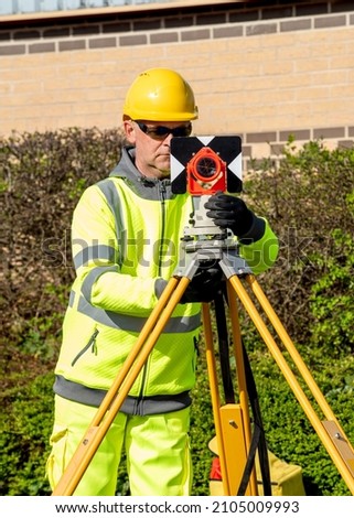Site engineer installing backsight prism above control points on construction site