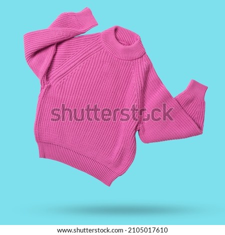 pink wool knitted sweater flies as if dancing, hands up, levitates on cyan background, shopping concept