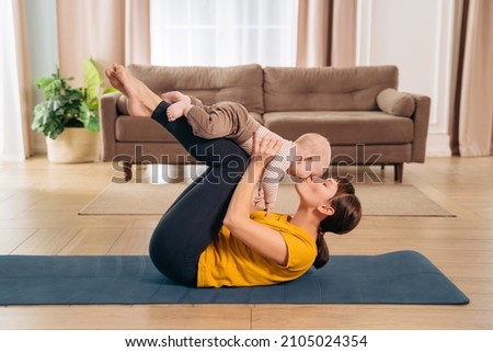 Sport with baby. Fit mom kissing her toddler son while holding him on her legs and doing postpartum recovery exercise on fitness mat at home.
Sporty woman exercising together with her little baby Royalty-Free Stock Photo #2105024354