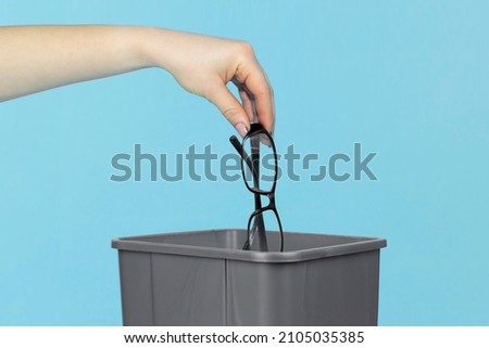 throw glasses in trash bin, glasses in hand in front of trash can, vision treatment concept Royalty-Free Stock Photo #2105035385
