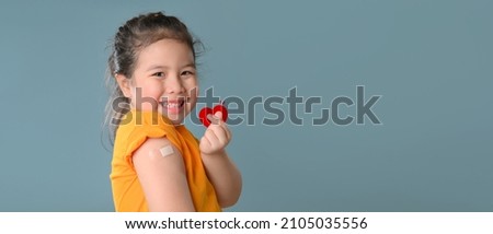 Coronavirus Vaccination Advertisement. Happy Vaccinated Little asian child girl Showing Arm With Plaster Bandage After Covid-19 Vaccine Injection Posing Over Blue Background, Smiling To Camera. New no Royalty-Free Stock Photo #2105035556