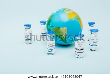 covid-19 omicron variant vaccine bottles near globe on blue background