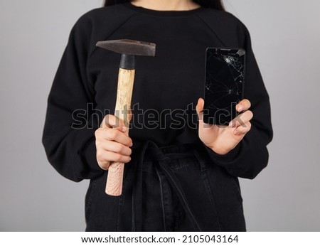 Broken phone and hammer in the hand of a caucasian woman.