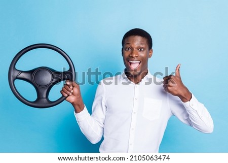Photo of cute charming dark skin guy dressed formal shirt driving car showing thumb up smiling isolated blue color background